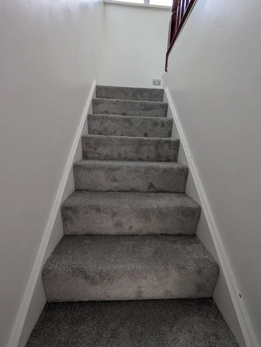 Grey twist carpet fitted up a full flight of stairs with a mahogany newel post at the top.